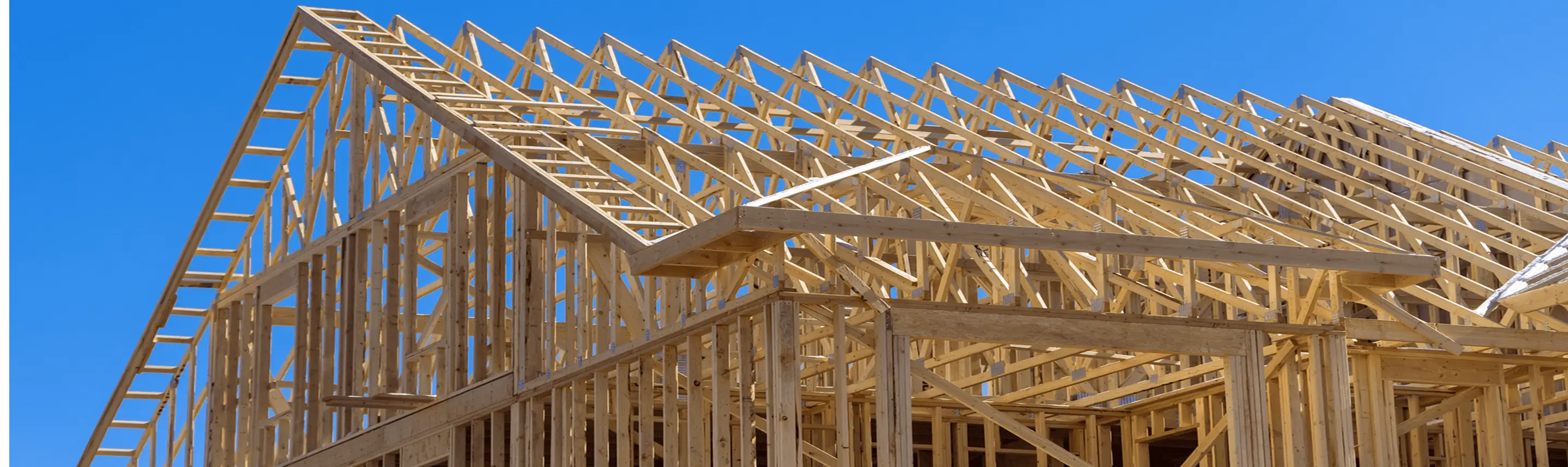 Wooden house frame under clear blue sky